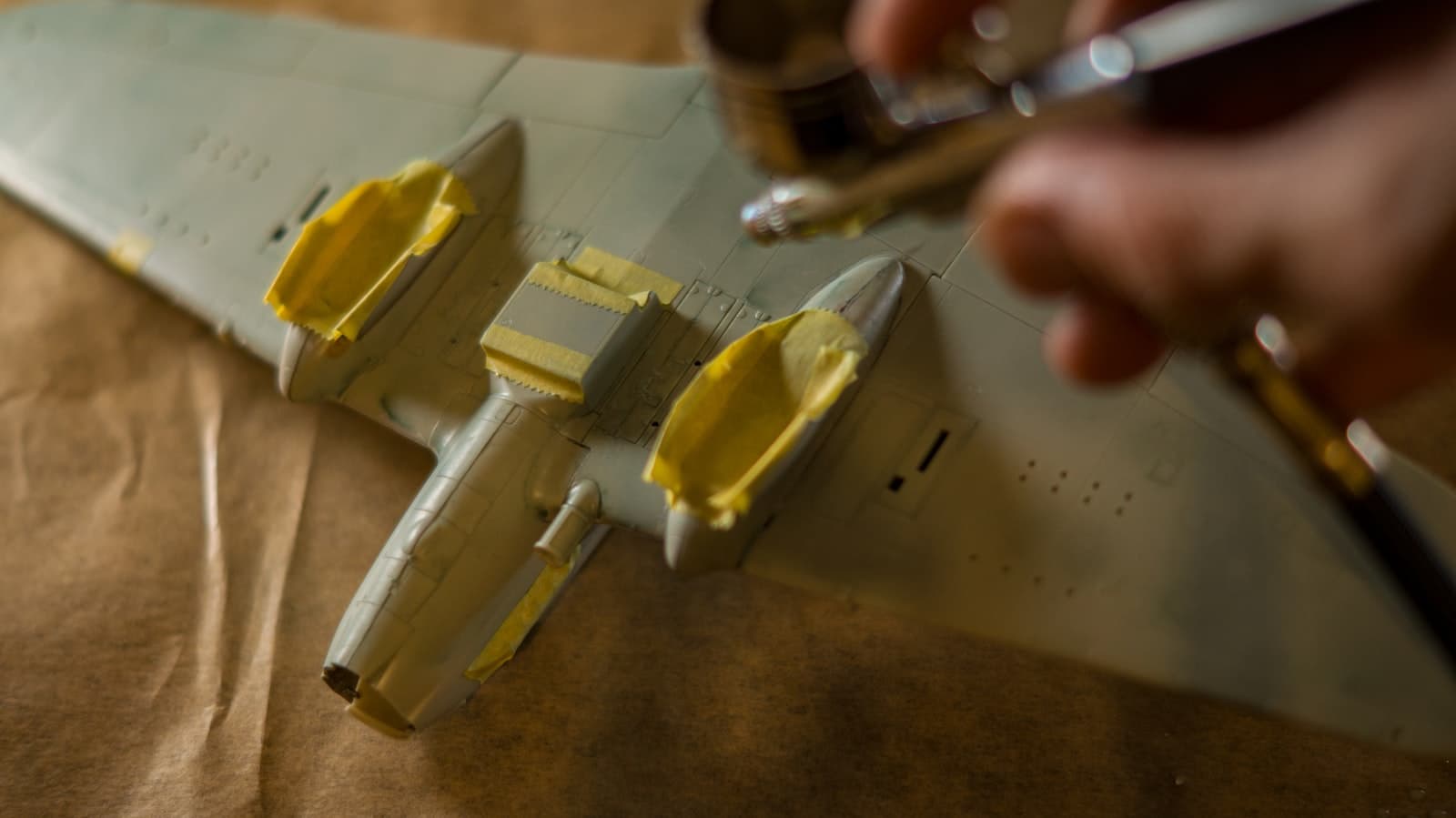 Hands assembling a model aircraft wing on a workbench